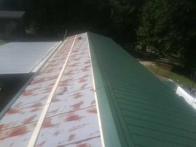 Old rusted panels beside newly installed green metal roofing — Wind Damage Roof Repair by Roofing Brothers in Statesboro