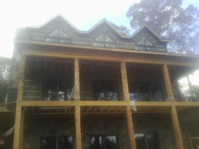 Dormers and porch framing on a large log home under construction — Roof Coating work by our crew in Statesboro