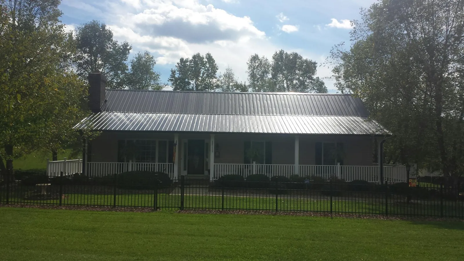 Gray metal roof on a brick ranch with a full width front porch — Gutter Guard Installation work by our crew in Statesboro