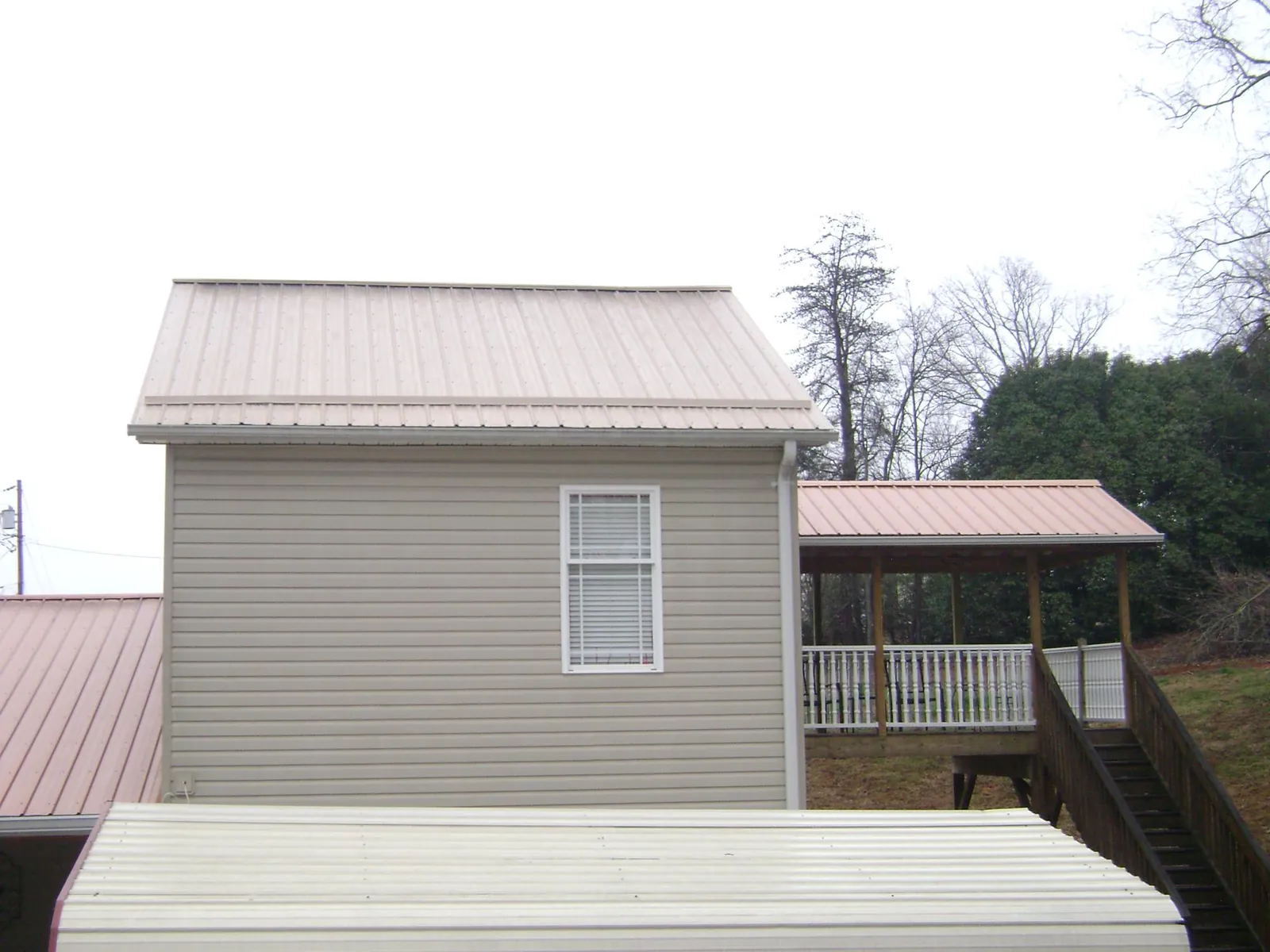 Tan metal roofs on a two story addition and attached porch, from a Roof Replacement job in Statesboro