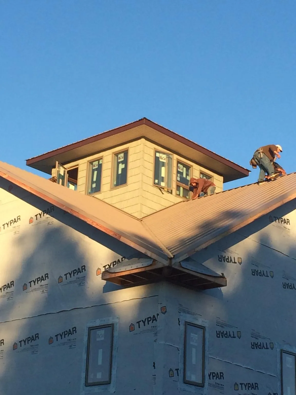 Roofers working around a rooftop cupola on a new metal roof at sunset — Roof Waterproofing in Statesboro by Roofing Brothers